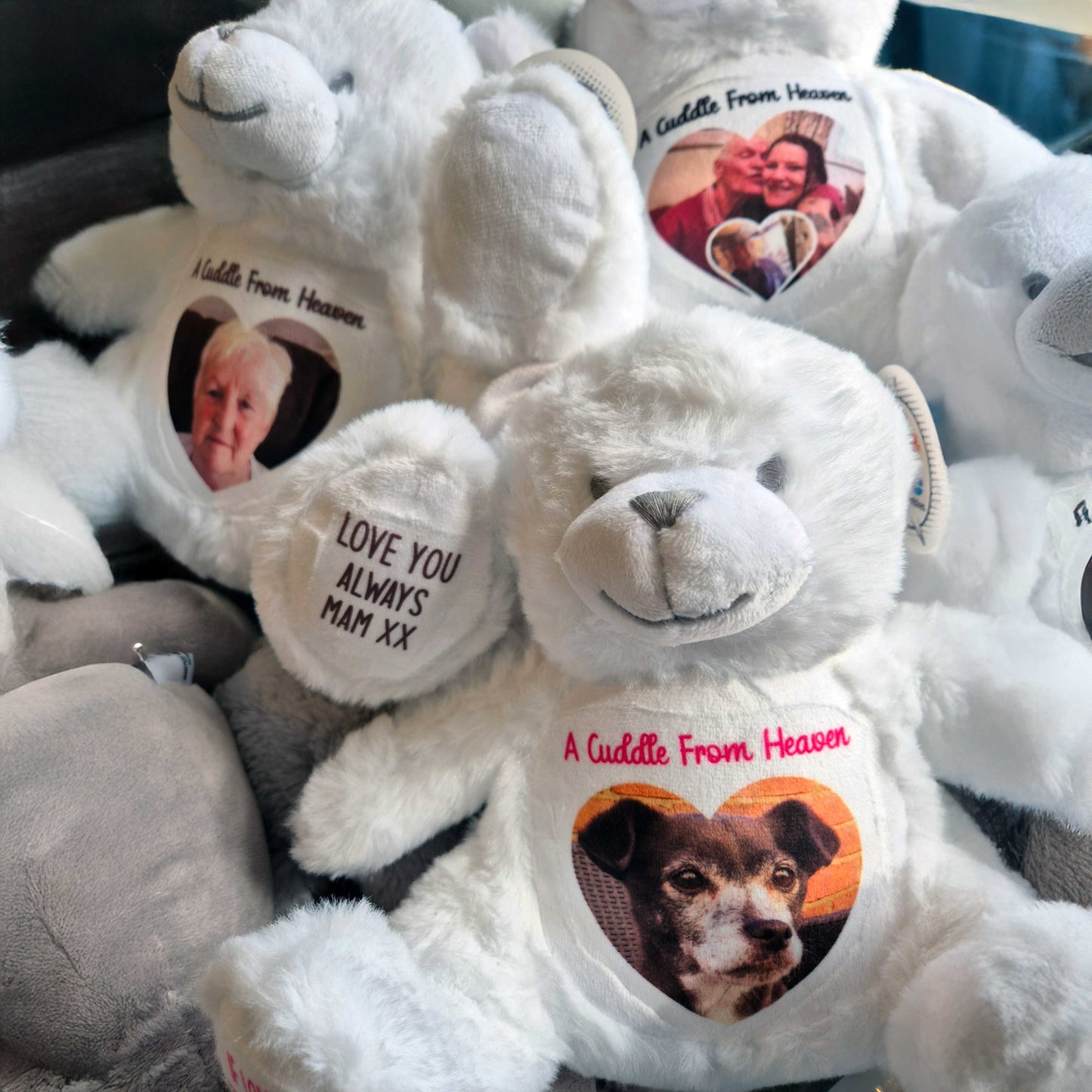 Stack of white angel teddy bears with personalised messages and photos on them CFHANG