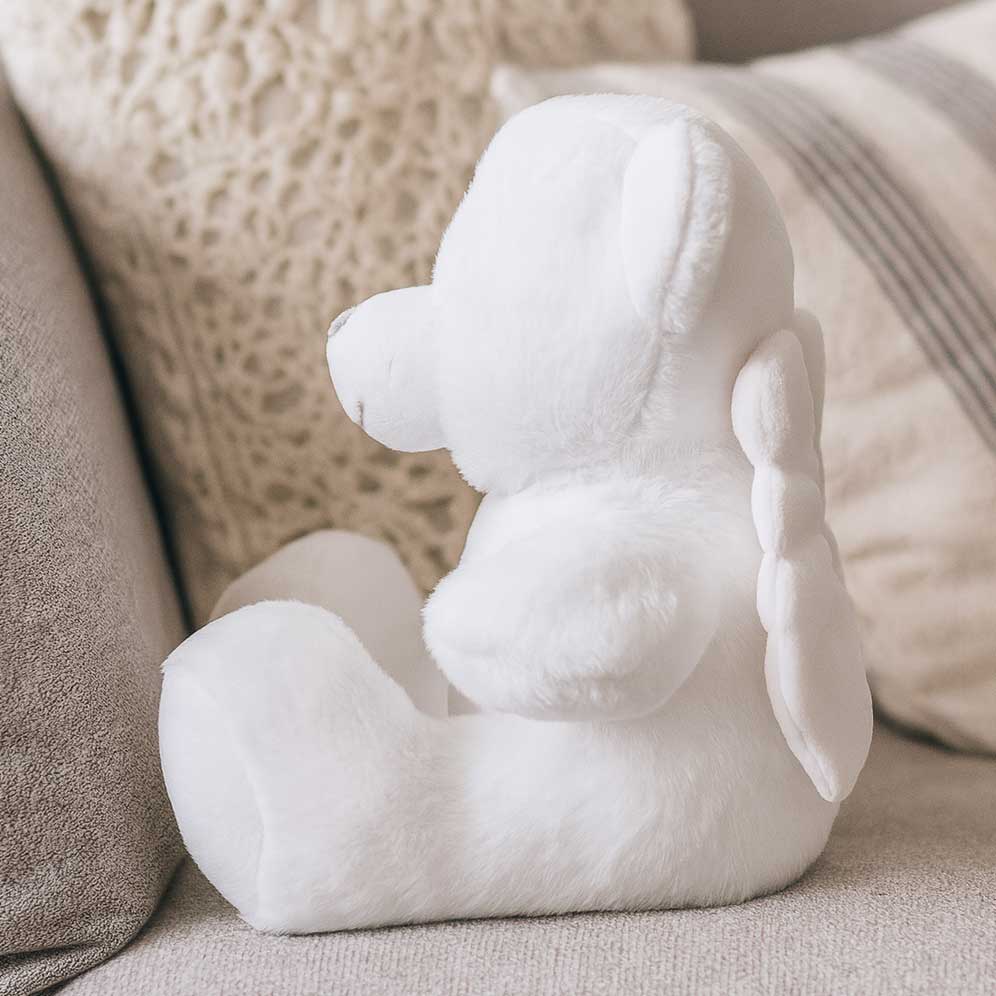 White angel plush toy side view on a beige couch CFHANG