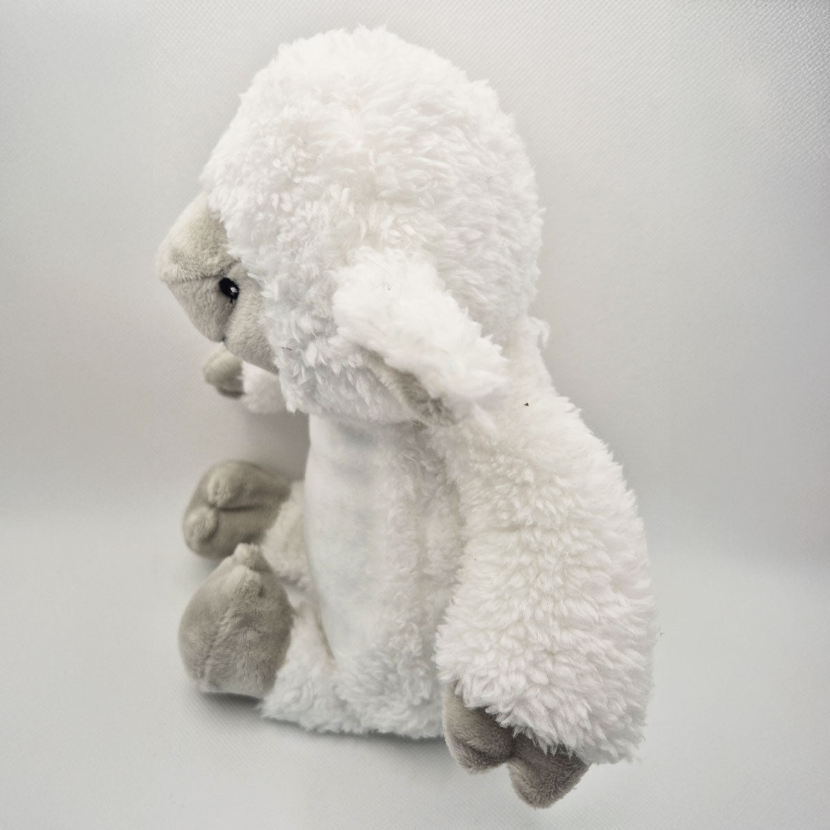 Side view of plush toy lamb on a white background