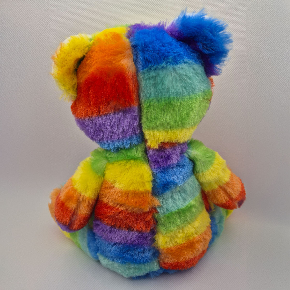 Multicolored striped teddy bear on a white background