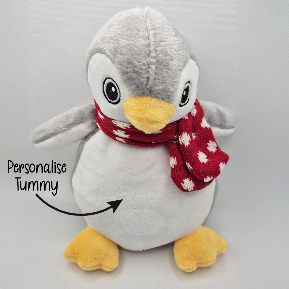 Plush penguin teddy with a red scarf on a grey background