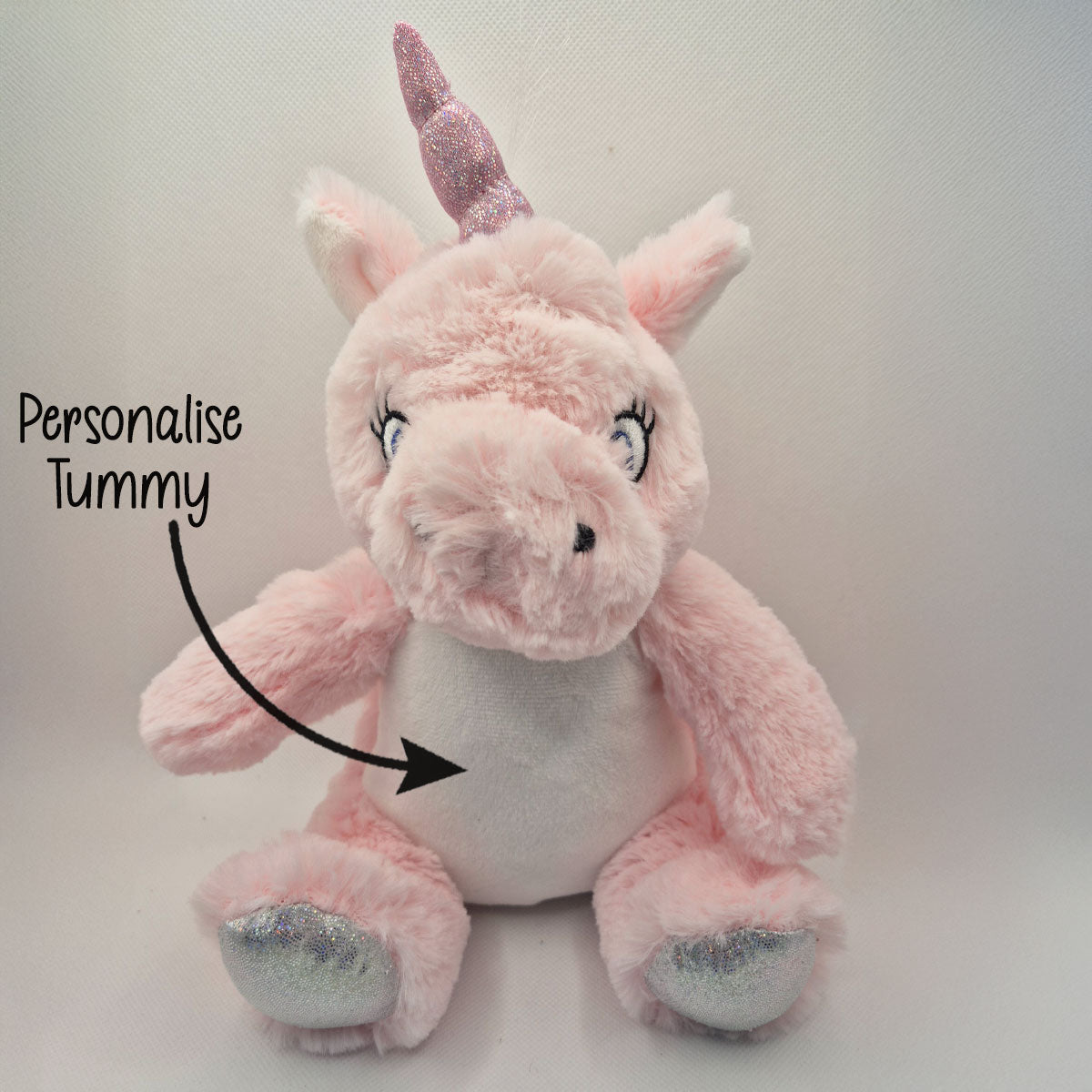 Pink plush unicorn teddy with a customisable tummy on a light grey background