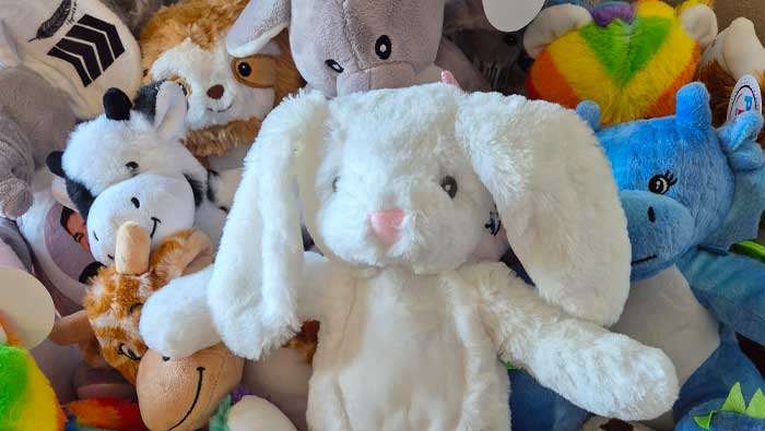 White stuffed bunny surrounded by other colourful plush toys