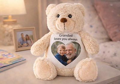 Brown teddy bear with a heart-shaped photo printed on the tummy sat on a table.