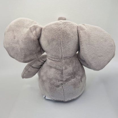 Back view of a grey plush elephant toy on a light grey background